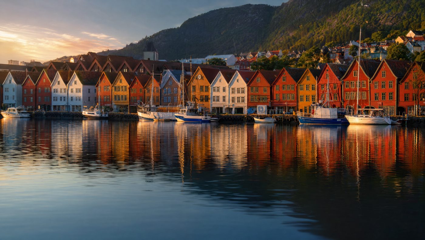 Bryggen wharf in Bergen at sunset, colourful wooden buildings reflected in the harbour